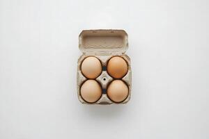 Four organic eggs sit nestled inside a partially opened carton on a simple background photo