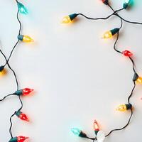 Multicolored holiday lights create a bright border on a solid white background for text photo