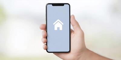 A hand holding a smartphone with a house icon on the screen photo