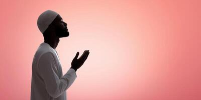 Man in traditional attire praying with hands raised against a soft gradient background showcasing spirituality and devotion concept photo
