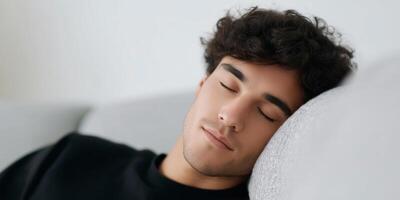 Young man with curly hair is peacefully resting on a soft couch, showcasing a serene atmosphere and relaxed expression, embodying tranquility and comfort in a cozy environment photo