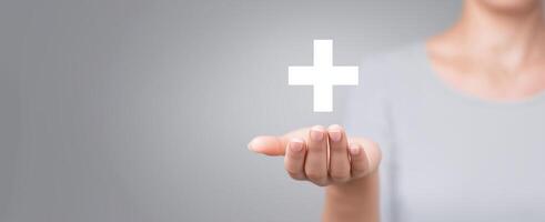 Hand of a woman presenting a white plus symbol in a minimalistic environment, symbolizing health, positivity, and support in a modern context with soft lighting photo