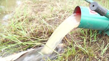 A green and red water pump is being used to fill a bucket video
