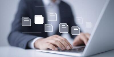 Business professional working on laptop with digital file icons floating above in modern office environment showcasing technology and productivity concepts photo