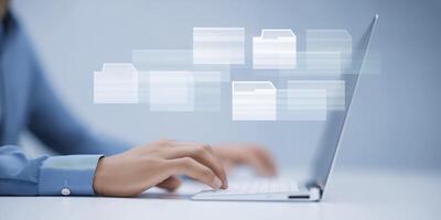 Person using laptop with digital file icons floating above, representing data management and organization in a modern workspace with copy space photo