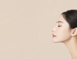 Profile view of a serene Asian woman with smooth skin and elegant features against a soft beige background, showcasing beauty and tranquility in a minimalist style photo