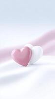 Two glossy hearts, one pink and one white, resting on a soft fabric surface, creating a romantic and serene atmosphere with gentle pastel colors and smooth textures photo
