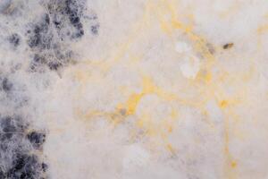 Detailed close-up of elegant white and gold marble texture with black patches photo