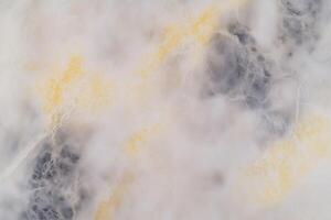Abstract marble texture with swirling white, gray, and yellow patterns photo
