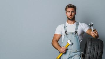 Focused Mechanic Posing with Wrench and Tire in Clean Design photo