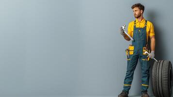 Mechanic in Overalls Holding Wrench and Tire in Neutral Space photo
