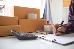 A man is writing on a notepad while holding a pen and a calculator photo