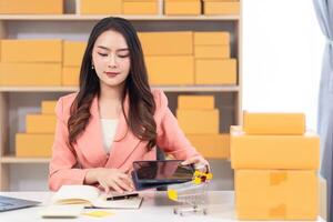 Asian woman working at desk with laptop and boxes photo