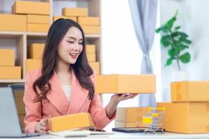 Asian woman in office holding boxes and laptop photo