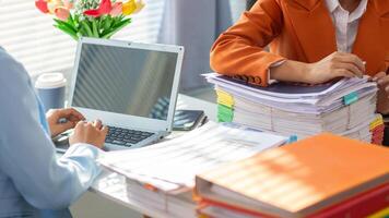 Two women working on a laptop at a desk photo