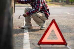 A man fixing a car tire with a wrench photo