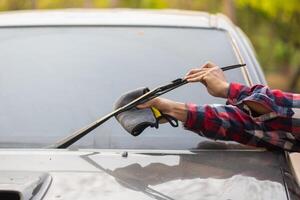 A man is using a car windshield wiper to clean the windshield photo