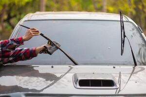 A man is using a car windshield wiper to clean it photo