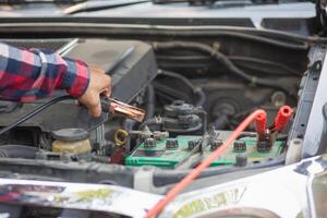 A man is using an electric tool to check the battery in a car photo