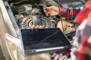 A man holding a tablet computer and looking at a car engine photo