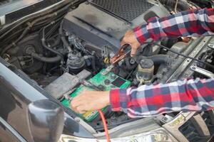 A man is working on a car with a battery photo