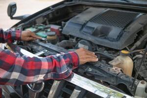The man is checking engine and condition of car to fix it properly and safely before traveling long distances. The man is checking condition of the car and the engine before traveling for safety. photo
