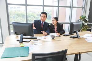 Business colleagues discussing data at desk, Asian professional business meeting in office, Supervisor training and suggesting about work to colleagues, Businesspeople team meeting in modern office photo