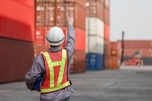 Back view of Engineer man working at industry containers cargo, Logistics professional inspecting containers box at shipping yard photo