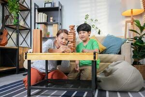 Mother and Son Playing Block Game in Living Room, Happy Asian Family Bonding with Fun Indoor Game, Parent and Child Enjoying Quality Time Together photo