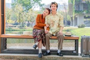 Couple Resting in Park on a Sunny Day, Joyful Young Asian People Dating in a Green Park Setting, Affectionate Couple Traveling and Sitting on Bench photo