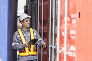 Engineer man with tablet inspecting cargo containers, Foreman worker checking containers box at shipping container yard photo
