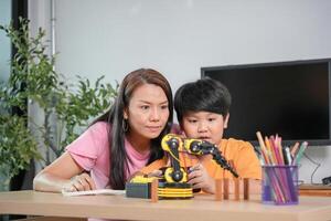 Mother and Son Learning Robotics Together, Young Boy Engaged in STEM Education with Robot Arm, Parent and Child Explore Technology with Robotic Kit photo