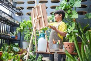 Asian Kid Boy Artist Drawing with Colorful Paints at Home, Child Boy Painting on Easel in Garden at Home photo