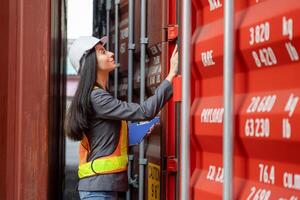 Female engineer with clipboard inspecting containers box, Foreman worker checking containers box at shipping container yard photo