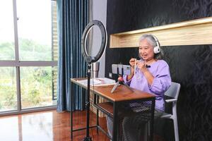Senior Woman Creating Online Content Live Streaming or Vlogging from Home, Mature Woman Using Technology for Online Selling at Home photo