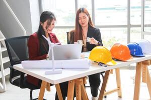 Smiling Female Architects Collaborating on Sustainable Design, Young Asian Engineers Discussing Building Plans and Green Energy, Professional Women Working on Architectural Project photo