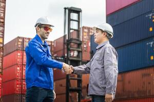 Engineers Shaking Hands at a Shipping Container Yard, Industrial Professionals Seal a Deal at a Port, Diverse Engineers Working Together in a Container Terminal photo