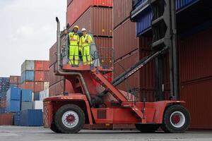 Engineer and foreman dock worker inspecting containers box at shipping yard, Inspectors standing on top of a containers handlers machine at container yard photo