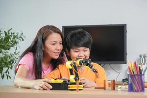 Mother and Son Learning Robotics Together, Young Boy Engaged in STEM Education with Robot Arm photo