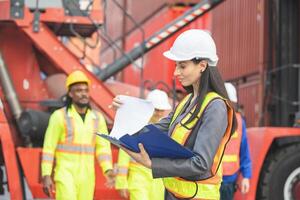 Female engineers managing cargo operations, Engineer and foreman dock worker checking containers box at shipping yard photo