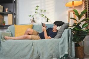Boy Relaxing on Sofa with Headphone and Phones, Child Using Digital Device on Couch, Comfortable Kid Enjoying Entertainment on a Tablet photo