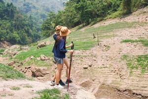 Young Asian Hikers Exploring a Dry Riverbed in the Mountains, Friends with Trekking Poles on a Nature Trail photo