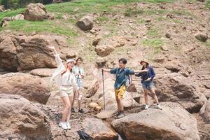 Group of Friends Enjoying a Fun Hike on Rocky Terrain, Happy Hikers Posing and Waving in a Natural Landscape, Young People Exploring Outdoors on a Summer Adventure photo
