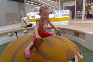 Curly-haired child of three plays in a play center. People photo
