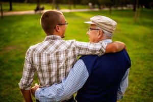 Caucasian grandfather and grandson hugging each other tightly in a park, reflecting real moments of family love. photo