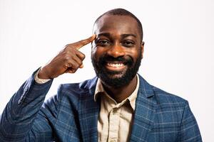 Confident African American businessman in a suit smiling with pride, pointing to his head as a gesture of having a bright idea. photo