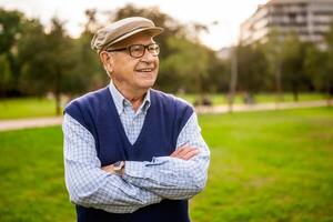 Portrait of cheerful elderly man smiling while relaxing outdoors in a sunny park, enjoying nature and leisure time. photo
