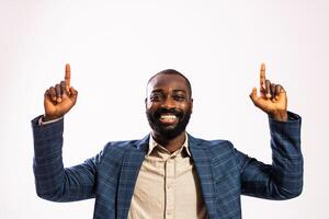 Confident African American businessman in a suit pointing upward with a toothy smile and a blank space for advertisement. photo