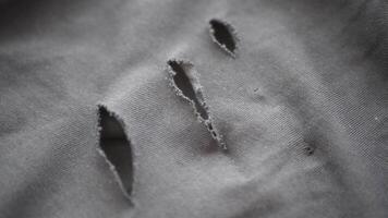 Holes in black fabric reveal wear and tear from usage video