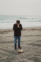 Man Flipping The Pages Of The Bible Book While Praying By The Ocean photo